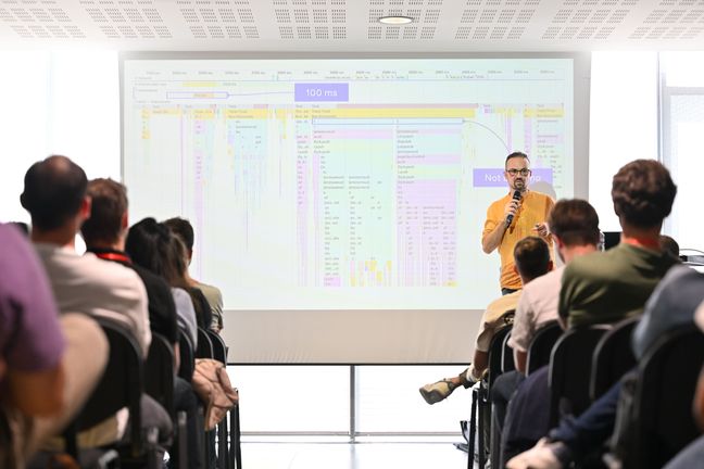 Andrea Verlicchi speaking on stage at We Love Speed, Nantes. The slide shows the flame chart of the performance trace run after an INP optimization